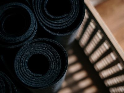 Rolled up yoga mat on a dark textured surface